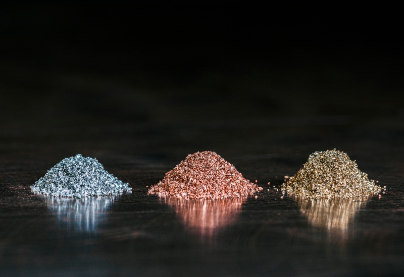 Small piles of ferrous and non-ferrous metal granules on a dark surface in Vancouver, BC