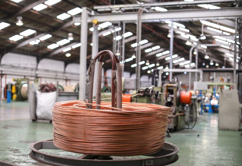 Coiled copper wire spool inside a metal processing factory with machinery in Vancouver, BC