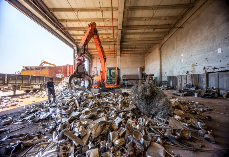 Excavator sorting metal scrap inside an industrial recycling warehouse in Vancouver, BC