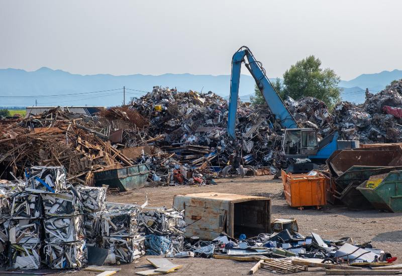 Scrap metal recycling yard with an excavator and large piles of industrial metal in Vancouver, BC